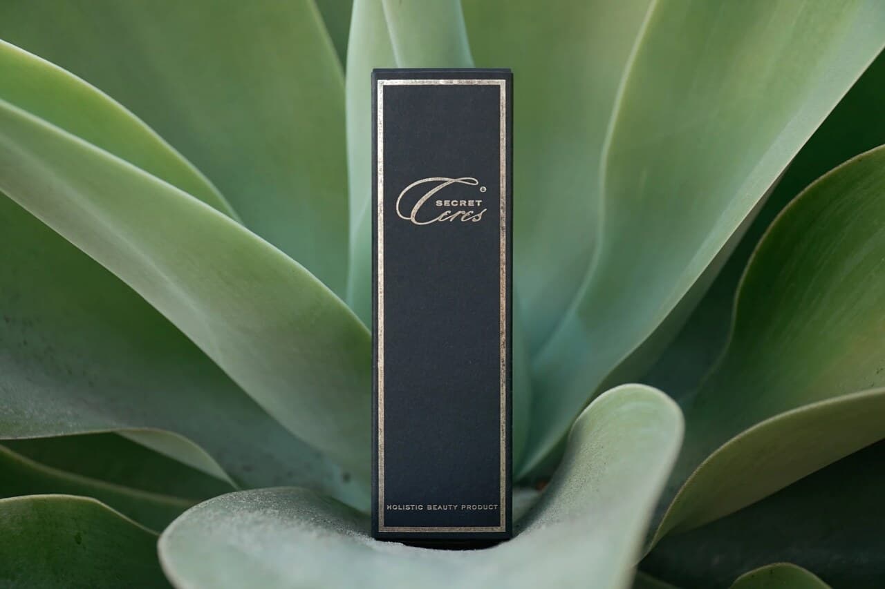 Secret Ceres by Awake Your Inner Body — navy and gold packaging photographed against a large agave plant. The product as the maker presents it.